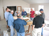 JPEG 74KB - A number of the men at their morning meeting getting ready for the day's activities.