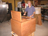 Scott Butler is doing finish work on a cabinet by installing the doors.