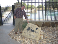 A South Texas Children's Home staff member pointing out their logo painted on a large rock.